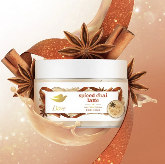 A jar of Dove Spiced Chai Latte Limited Edition Body Scrub, styled with cinnamon sticks, star anise, and a warm orange glitter ribbon on a soft peach background. purchase from www.americanbodycare.co.uk