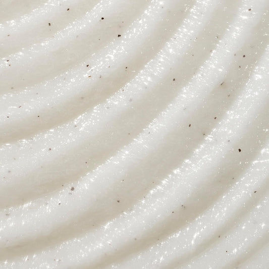 A close-up texture shot of a creamy, off-white whipped cosmetic or food product with diagonal ridges and tiny dark specks. purchase from www.americanbodycare.co.uk