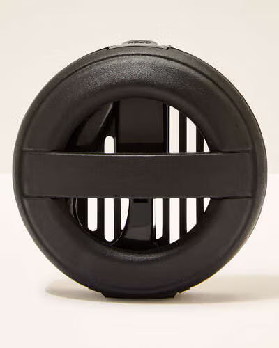 Black circular object with a central slit on a beige background. Purchase from www.americanbodycare.co.uk 