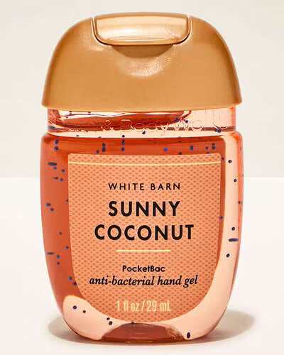 Hand gel bottle labeled 'Sunny Coconut' from White Barn on a beige background. Purchase from americanbodycare.co.uk 