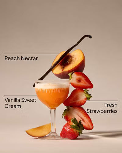 Cocktail with peach nectar, vanilla sweet cream, and fresh strawberries on a beige background. Purchase from americanbodycare.co.uk 
