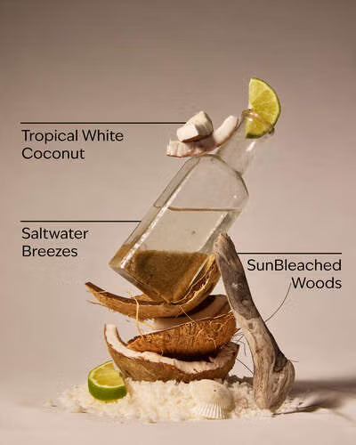 Decorative arrangement with a bottle, coconuts, and lime slices on a neutral background. Purchase from americanbodycare.co.uk 