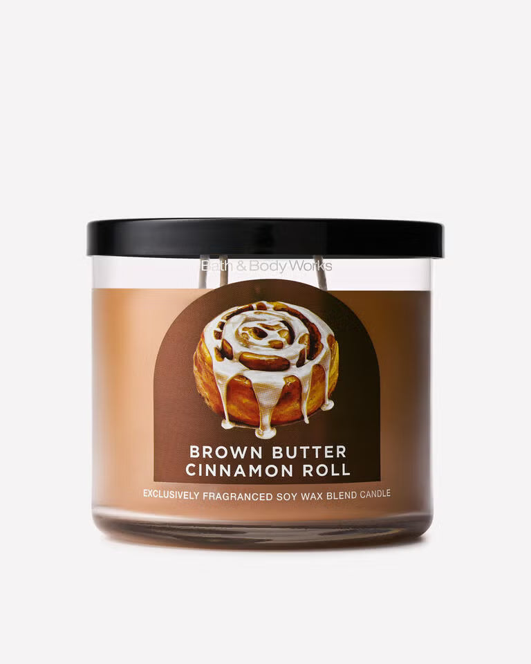A Brown Butter Cinnamon Roll scented soy wax candle by Black Body Works in a clear glass jar with a black lid and a brown label featuring a cinnamon roll illustration. Purchase from www.americanbodycare.co.uk 