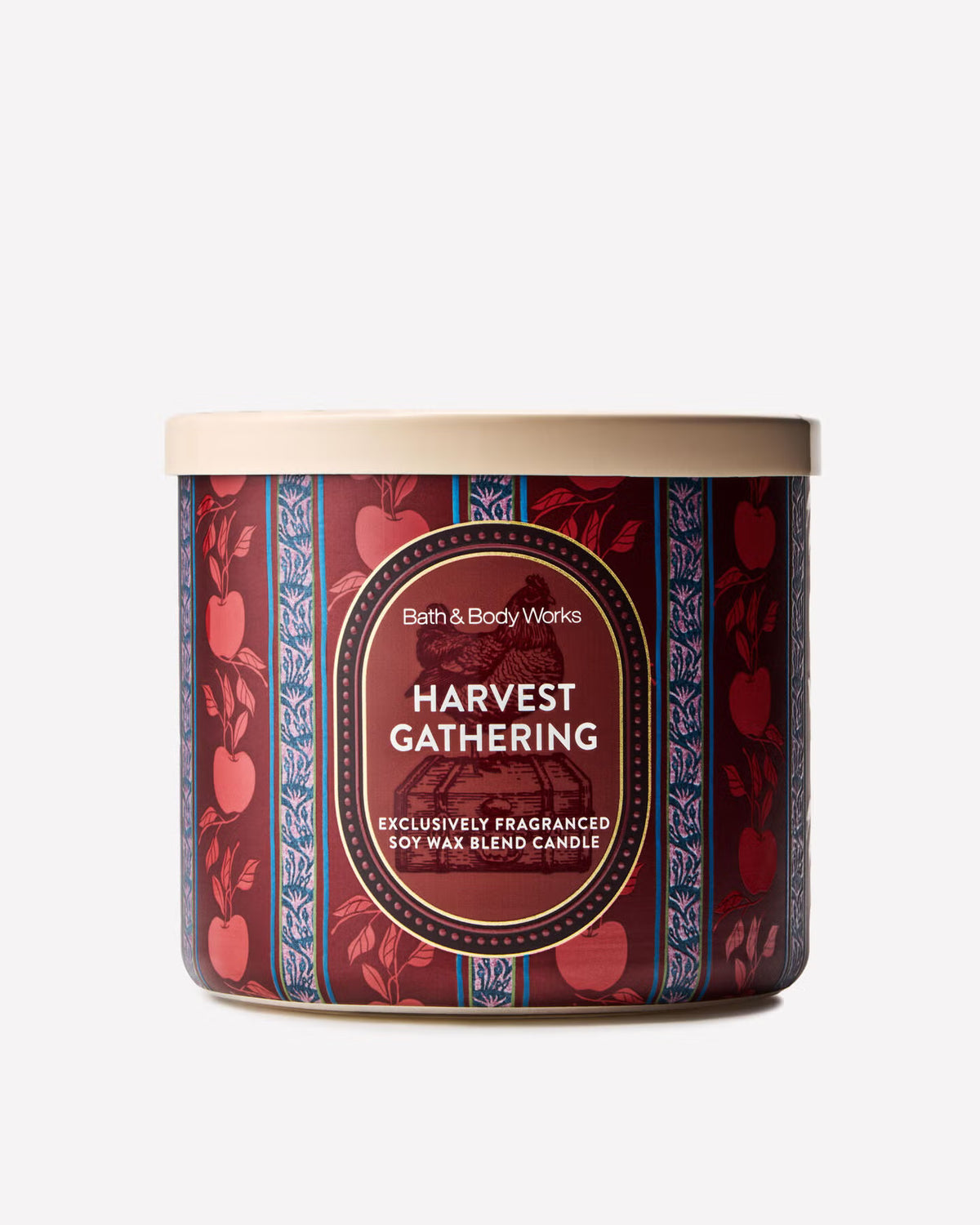A Bath & Body Works 'Harvest Gathering' soy wax blend candle in a cylindrical tin with a beige lid, featuring a dark red label with apple motifs and blue decorative borders. Purchase from www.americanbodycare.co.uk
