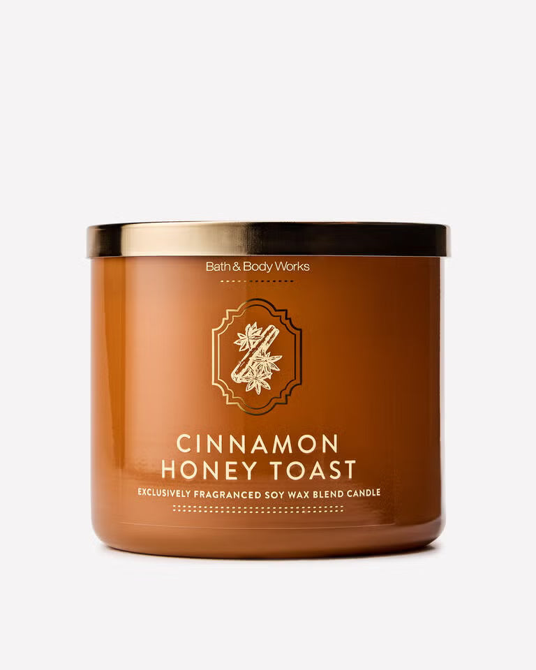 A Bath & Body Works Cinnamon Honey Toast soy wax candle in a brown amber jar with a gold lid, shown on a clean white background. Purchase from www.americanbodycare.co.uk 