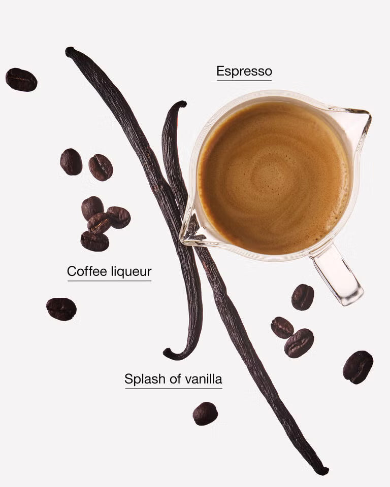 A clear glass pitcher filled with espresso sits on a light gray background, surrounded by coffee beans, two vanilla beans, and text labels reading 'Espresso', 'Coffee liqueur', and 'Splash of vanilla'. Purchase from www.americanbodycare.co.uk 