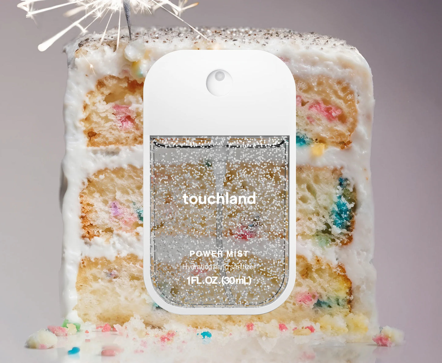 Touchland power mist bottle with a cake background. Purchase from americanbodycare.co.uk