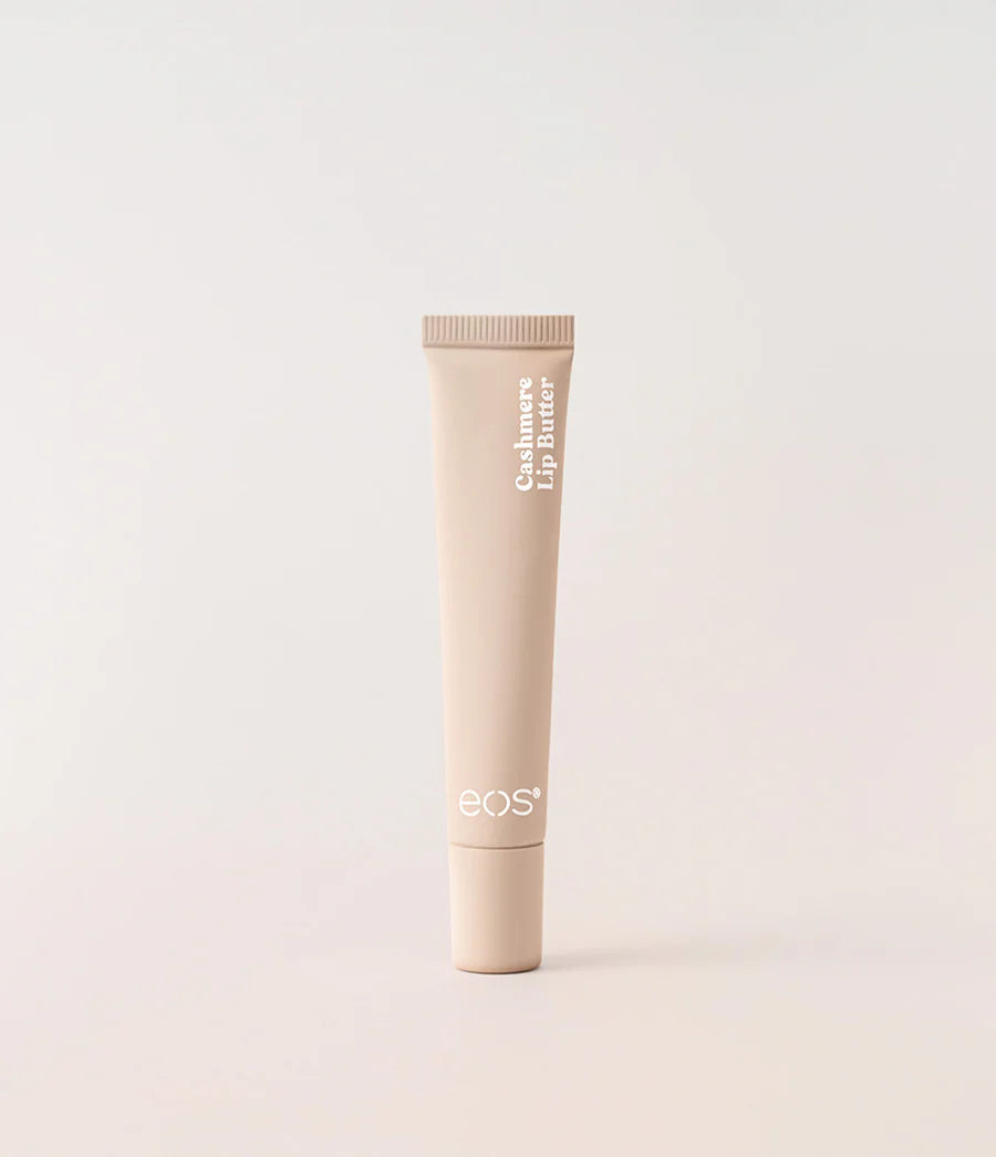 A single tube of EOS Cashmere Lip Butter in a light beige color, standing upright against a matching light beige background. Purchase from www.americanbodycare.co.uk 