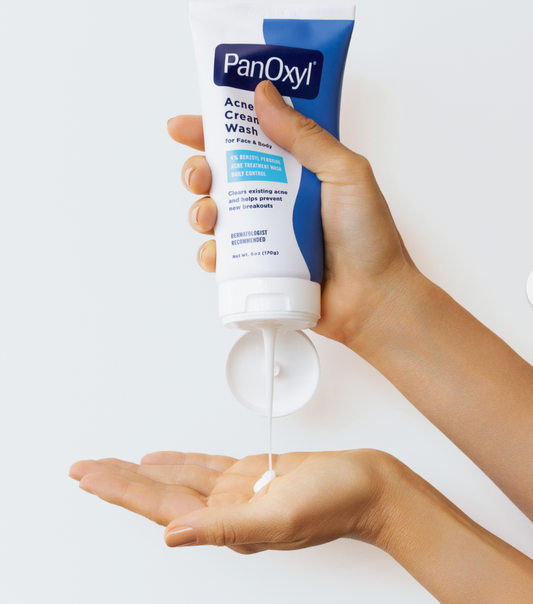 Hand holding a tube of PanOxyl Acne Cream Wash against a white background. Purchase from americanbodycare.co.uk