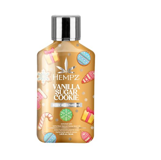 A bottle of Hempz Vanilla Sugar Cookie body moisturizer with a warm golden-brown background and festive cookie illustrations, topped with a reflective silver cap. purchase from www.americanbodycare.co.uk