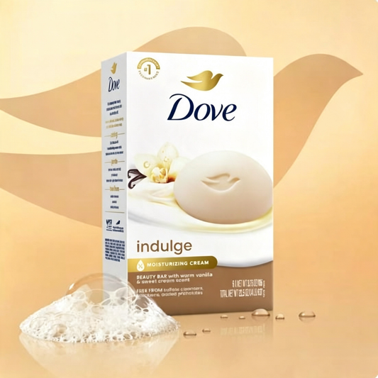 A box of Dove Indulge Moisturizing Cream beauty bar, shown standing upright with a single bar of soap and a small pile of lather in front, on a warm beige background with abstract leaf shapes. Purchase from www.americanbodycare.co.uk 
