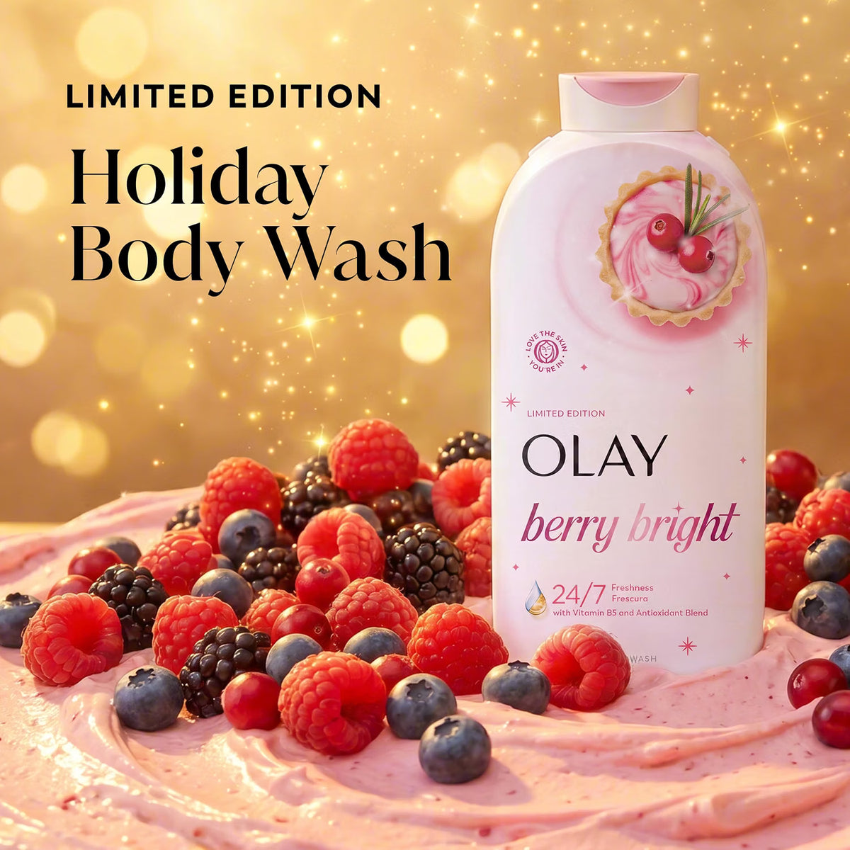 Olay Holiday Body Wash Limited Edition bottle in Berry Bright scent, styled on a pink whipped cream surface with fresh raspberries, blueberries, and blackberries against a sparkling gold bokeh background. purchase from www.americanbodycare.co.uk