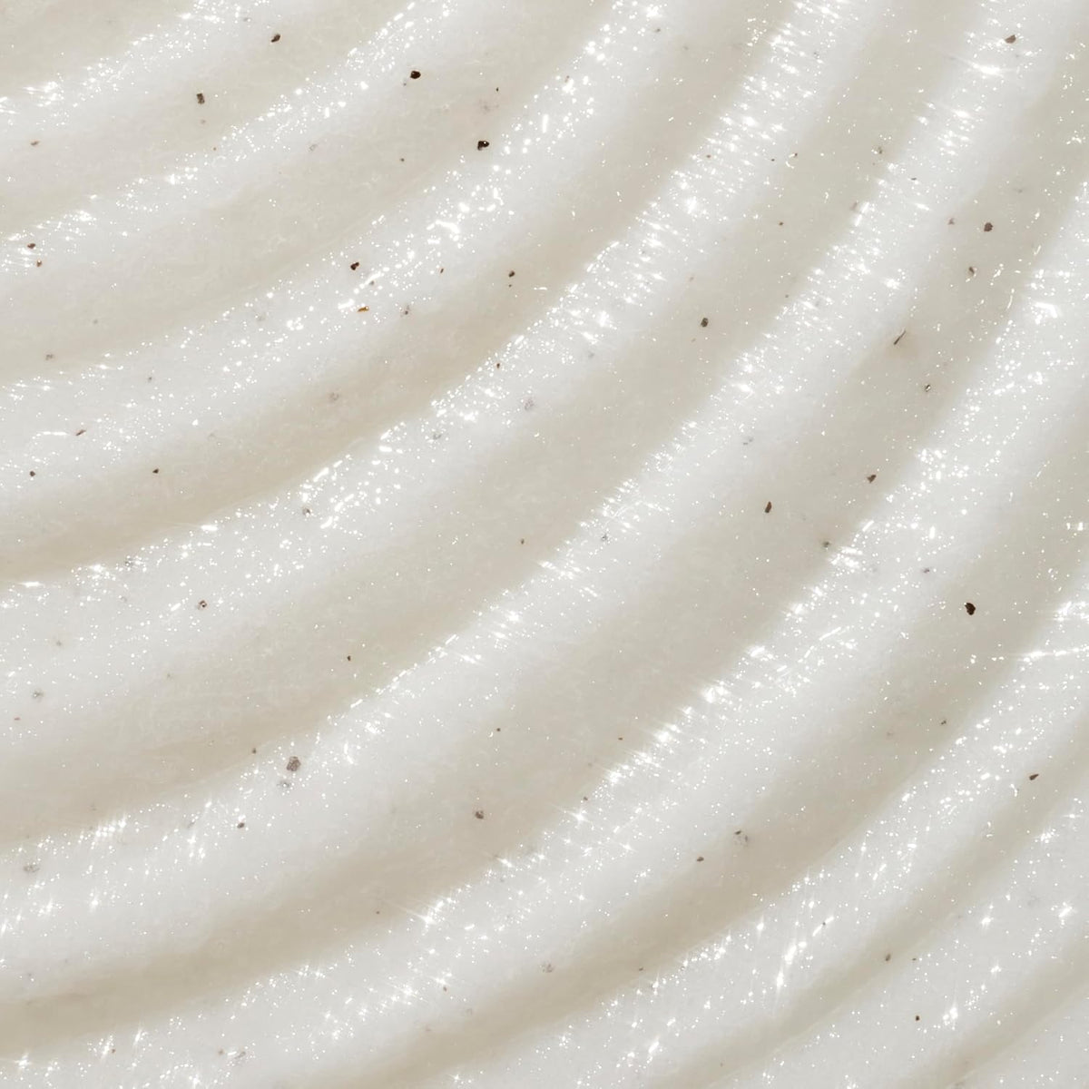 A close-up texture shot of a creamy, off-white whipped cosmetic or food product with diagonal ridges and tiny dark specks. purchase from www.americanbodycare.co.uk