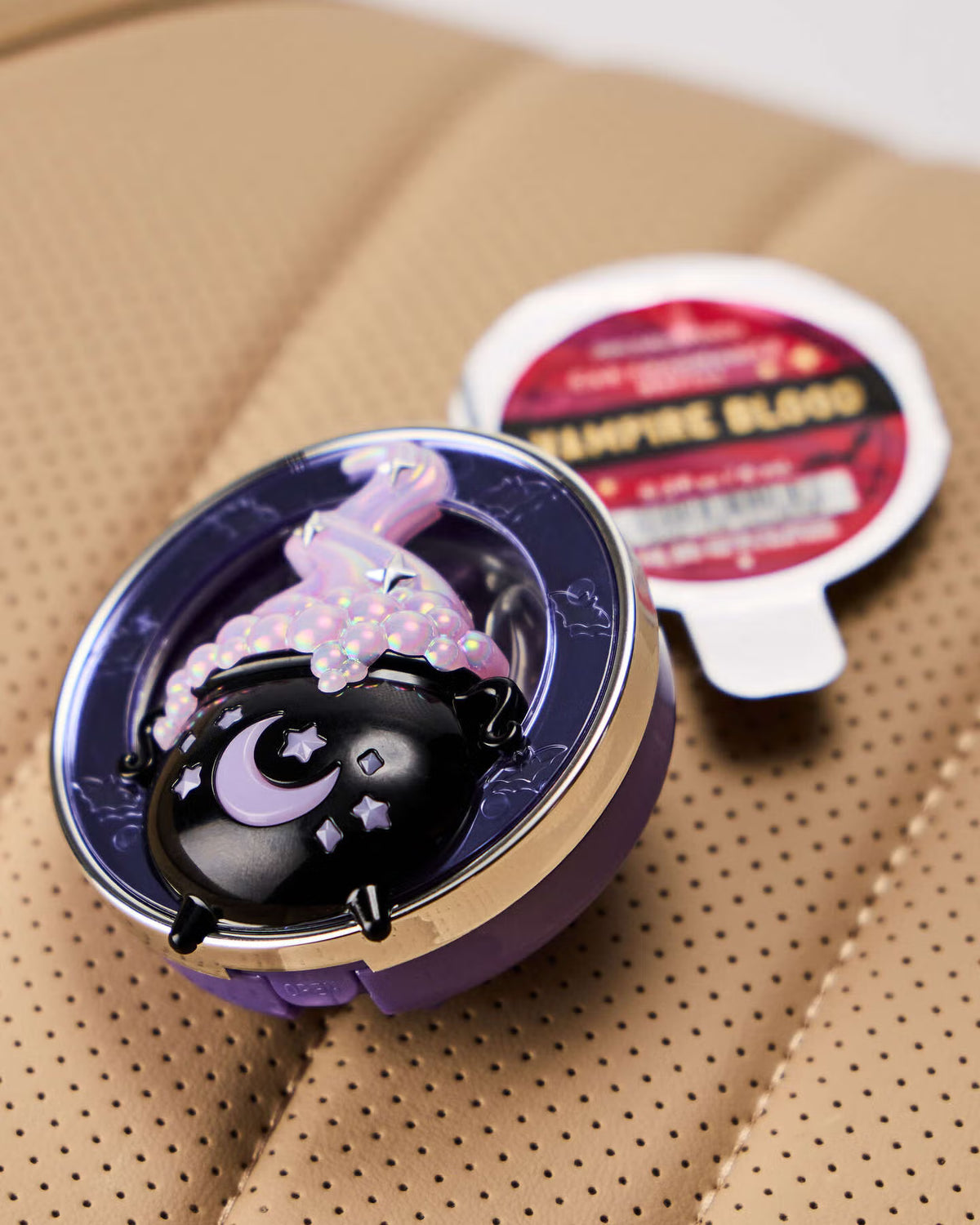 Compact mirror with a purple case and witch design on a beige surface. purchase from www.americanbodycare.co.uk