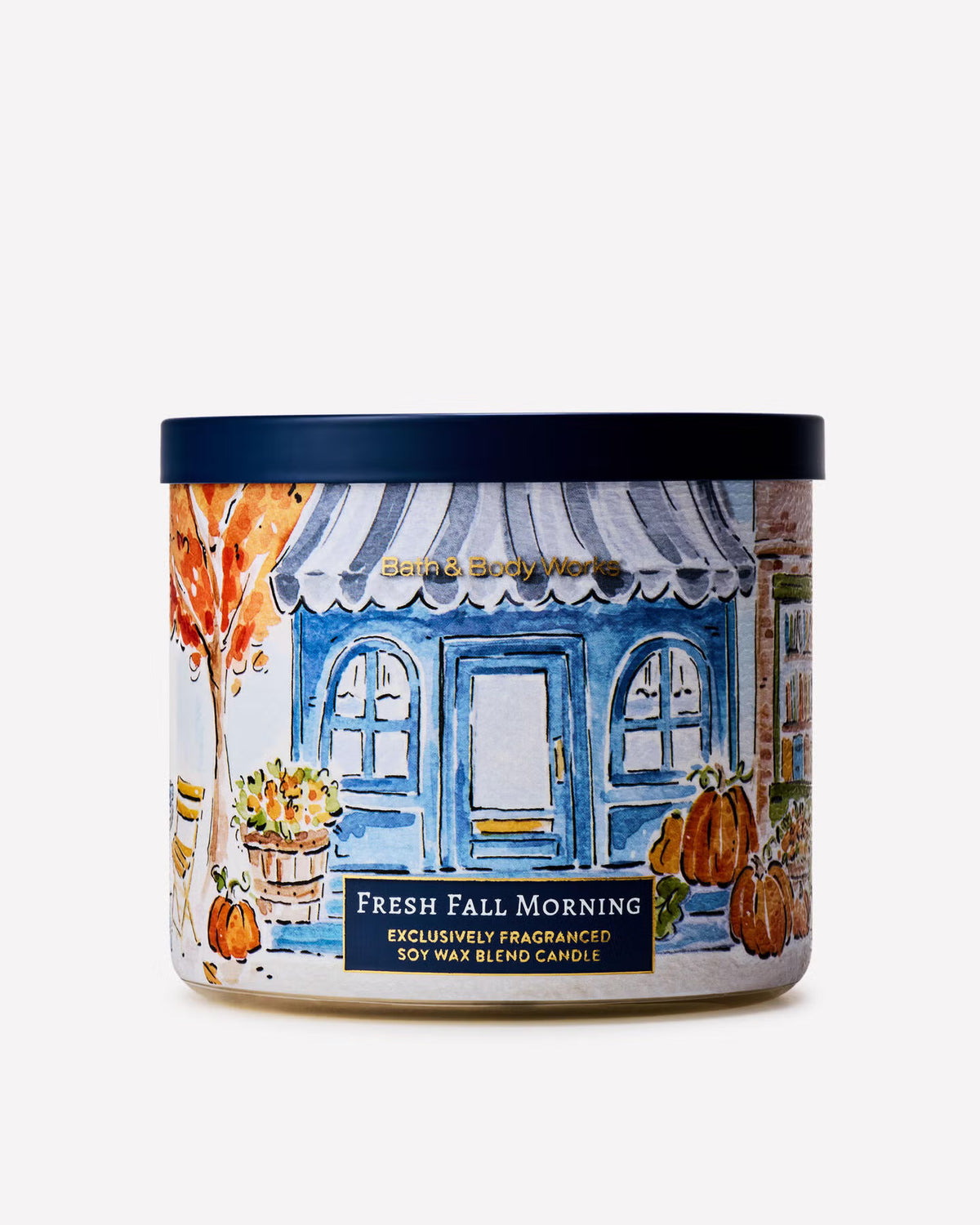 A jar of Swirls Body Works 'Fresh Fall Morning' soy wax candle, featuring an illustrated label of a blue storefront with pumpkins and an orange tree, set against a plain white background. Purchase from www.americanbodycare.co.uk