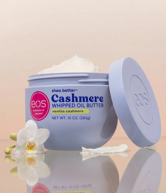 Eos Cashmere Whipped Oil Butter jar with a white flower on a beige background. Purchase from americanbodycare.co.uk