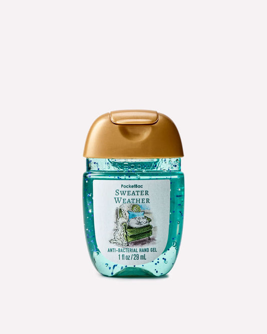 A bottle of Pocketbook Sweater Weather anti-bacterial hand gel, featuring a translucent teal-blue body with a metallic gold flip-top cap and a white label with a vintage illustration. purchase from www.americanbodycare.co.uk