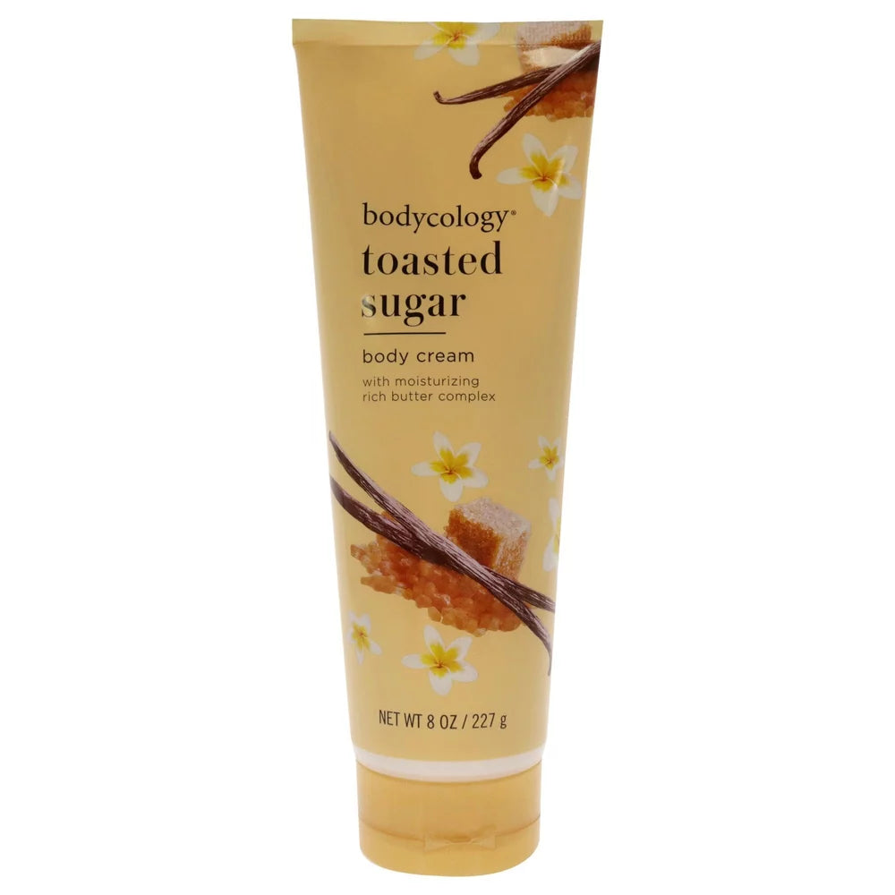 A 6 oz squeeze tube of bodycology Toasted Sugar Body Cream, featuring a warm beige and yellow design with illustrations of vanilla beans, honeycomb, and white flowers. purchase from www.americanbodycare.co.uk