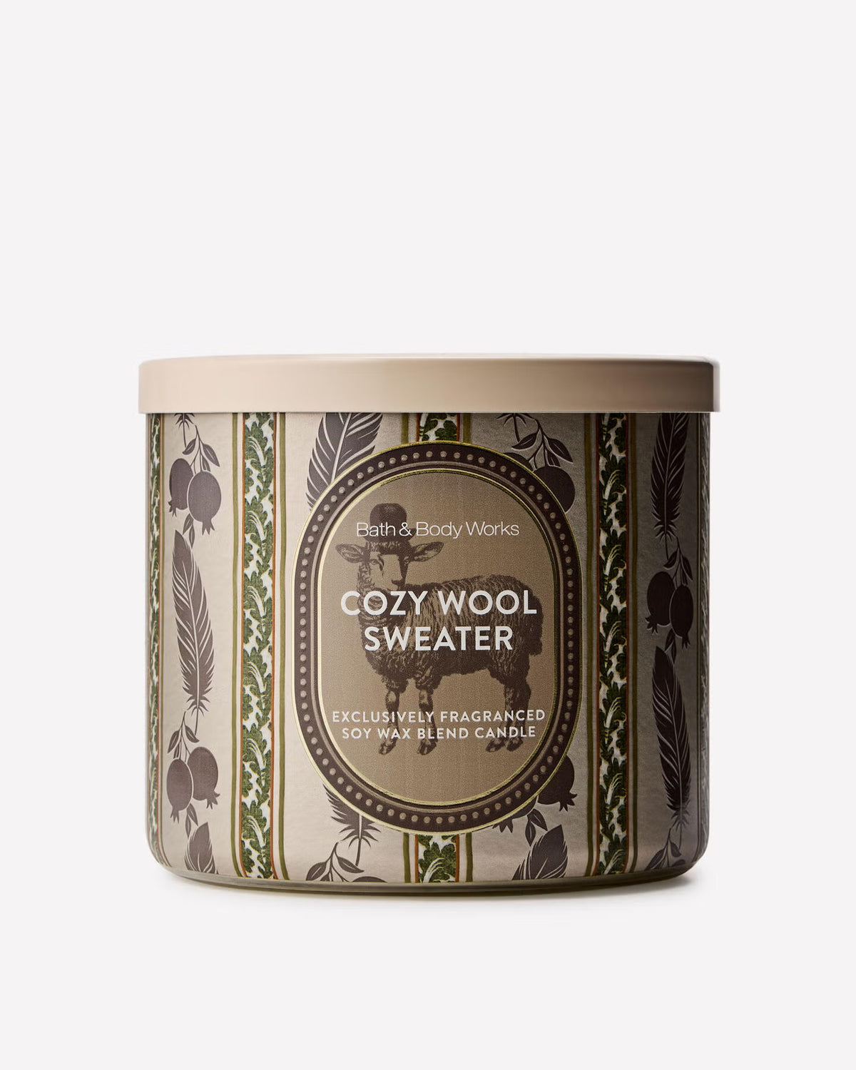 A cylindrical tin candle from Bath & Body Works in the Cozy Wool Sweater scent, featuring a beige lid and a patterned label with brown wool and green leaf motifs on a light gray background. Purchase from www.americanbodycare.co.uk